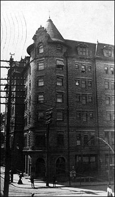 an old black and white photo of a large brick building on the corner of a street