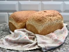 two loaves of bread sitting on top of a kitchen counter next to a towel