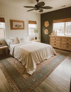 a bed sitting in a bedroom on top of a wooden floor next to two windows