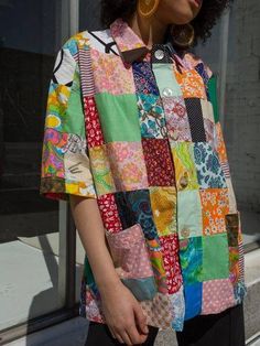 a woman with curly hair wearing a multicolored shirt