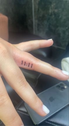 a woman's hand with the number 11 tattooed on her left thumb and fingers