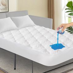 someone is pouring blue liquid on a mattress that's in front of a couch