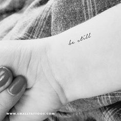 a woman's arm with a small tattoo on it that says be still in cursive writing