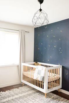 a baby's room decorated in blue and white with stars on the wall behind it