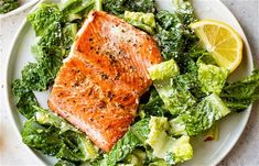 two plates with salmon, lettuce and lemon wedges