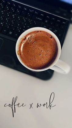 a cup of coffee sitting on top of a desk next to a laptop computer with the words coffee x work written across it