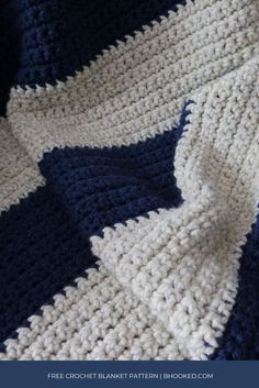 a crocheted blanket is laying on top of a bed with blue and white stripes