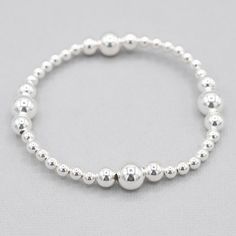 Want to feel instantly pulled together? You've found the perfect bracelet to add to your looks. This "currently classic" style is the answer. It's elevated and yet understated. The stations are precisely set to showcase the larger beads. You'll simply love wearing or gifting! 4mm sterling silver beads with 6 & 8mm larger beads set in four stations around bracelet. Select an all sterling style or mix your metals by adding a gold base. Easy wear and effortless stacking with sturdy stretch cord des Classic Adjustable Hand-strung Stretch Bracelet, Classic Hand-strung Stretch Bracelet For Everyday, Classic Everyday Stretch Bracelet, Classic Bracelets With 8mm Beads For Everyday, Classic Everyday Bracelet With 8mm Beads, Classic Everyday Beaded Bracelets With 8mm Beads, Classic Stackable Stretch Bracelet With Round Beads, Classic Sterling Silver Bracelet With Spacer Beads, Adjustable Classic Beaded Bracelets