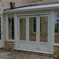 a house that has some doors and windows on the side of it with stone flooring