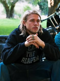 a man sitting on the ground with his hands folded