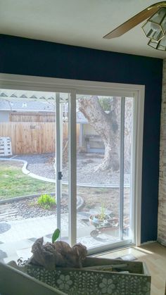 a living room with sliding glass doors leading to a patio area and a tree in the back yard