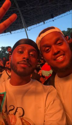 two men sitting next to each other in front of a crowd at a sporting event