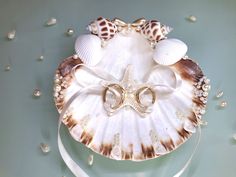 a decorative mask made out of seashells with pearls on the sides and ribbons around it