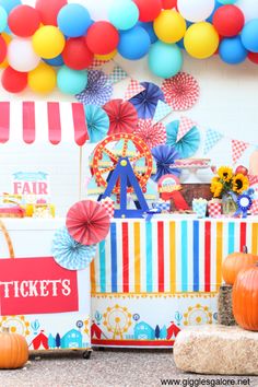 an amusement park themed birthday party with balloons and paper fan garlands on the ceiling