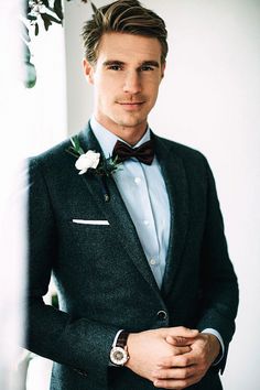 a man in a suit and bow tie is looking at the camera while wearing a watch