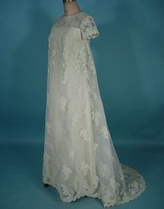 a white wedding dress on display against a blue background with a mannequin's head in the foreground