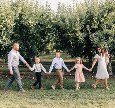 a group of people holding hands walking across a grass covered field