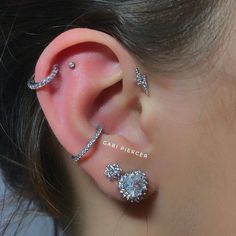 a woman wearing ear piercings with diamonds on her ears and behind the ear is an ear cuff