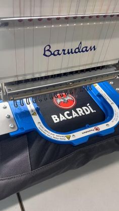 the back end of a machine that is cutting fabric with blue and white trim on it