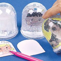 a hand is pointing at the inside of two plastic clochets with pictures on them