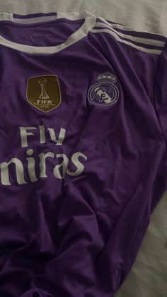 a purple soccer jersey with the word fiv miras printed on it, laying on a bed