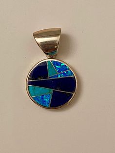 This beautifully well crafted Small Circle Pendant has been handmade by a Navajo Artisan. The Colors of the Pendant come from Lapis Lazuli, Turquoise and Blue Opal. The Pendant measures almost 1.25” long and over 3/4” wide. There are several pairs available in the design will vary. “Winds of Wisdom” (Lapis Lazuli, Turquoise and Blue Opal. The Navajo (Dine’) believe that the wind is a powerful source. The native tradition believes that at any moment, the blowing wind can inspire one with hope, re Southwestern Style Turquoise Round Pendant Jewelry, Spiritual Turquoise Blue Round Pendant Necklace, Turquoise Pendant Necklace With Inlay, Nickel-free Blue Turquoise Round Pendant Necklace, Southwestern Turquoise Inlay Pendant Necklace, Small Circle, Western Wedding, Circle Pendant, Turquoise Blue