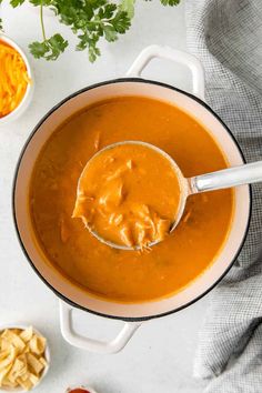 a bowl of soup with a spoon in it next to some crackers and parsley