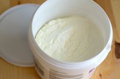 a white bucket filled with cream sitting on top of a wooden table