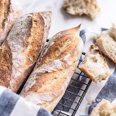 several loaves of bread sitting on top of a cooling rack next to a blue and white towel