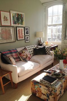 a living room filled with lots of furniture and pictures on the wall above it's windows