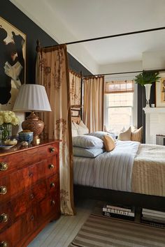 a bedroom with a four poster bed, dresser and lamp on the side table in front of it