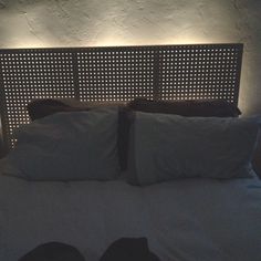 a bed with white sheets and pillows in front of a headboard that has lights on it