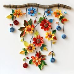 colorful flowers are hanging from a branch on the wall