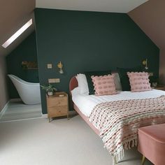 a bedroom with green walls and pink bedding in the corner next to a bathtub