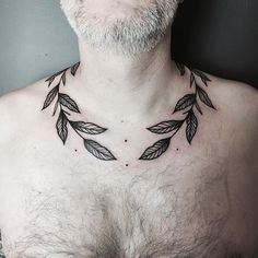 a man's chest with an arrow tattoo on his chest and leaves around the neck