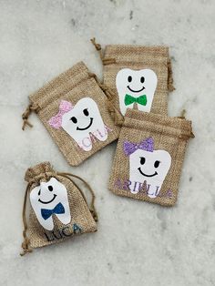 three small bags with faces on them sitting on the ground next to each other and one has a bow tie