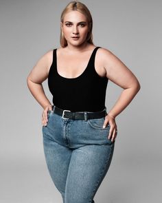 a woman in black shirt and jeans standing with her hands on hips