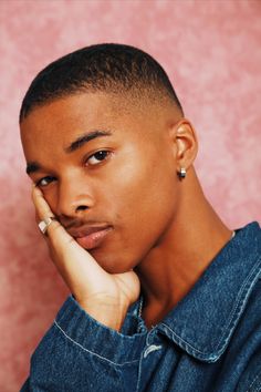 a close up of a person with a ring on his finger and wearing a denim shirt