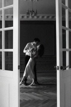 a man and woman kissing in an open doorway