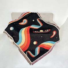 a black blanket with multicolored swirls and stars on it sitting on top of a white chair