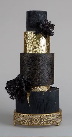 a three tiered cake with black and gold decorations