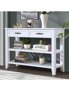 a white shelf with books and plants on top of it next to a potted plant