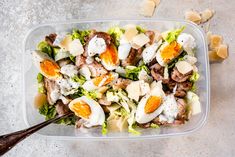 a salad in a plastic container with hard boiled eggs