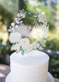 a wedding cake with white flowers and the word mr and mrs on it's top