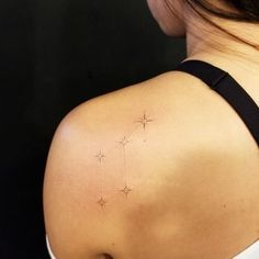 the back of a woman's shoulder with small stars on her upper arm and behind her left shoulder