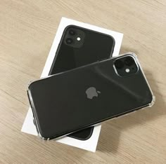 two black iphones sitting on top of a wooden table next to eachother