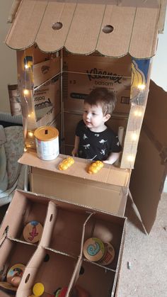 a young boy sitting inside of a cardboard box