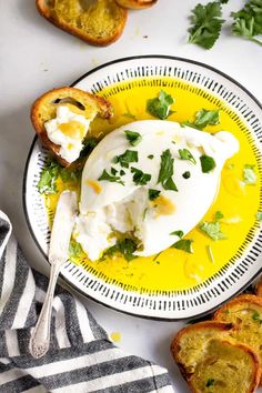 a plate with bread and an egg on it next to a bowl of sour cream