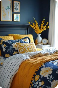 a bed with yellow and blue comforters in a bedroom next to two pictures on the wall