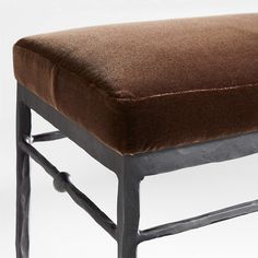 a brown velvet bench with metal legs and footrests on an isolated white background